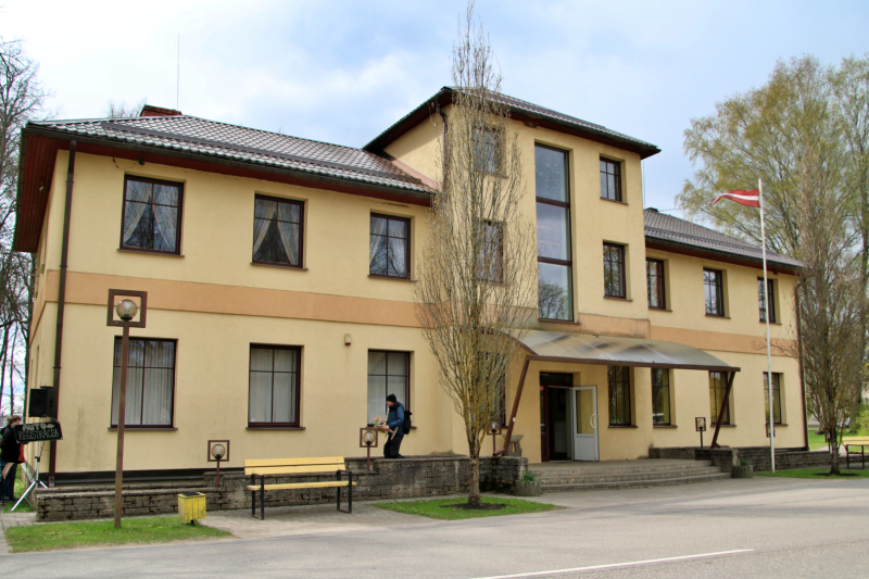 Gaiši brūna divstāvīga ēka ar Latvijas karogu