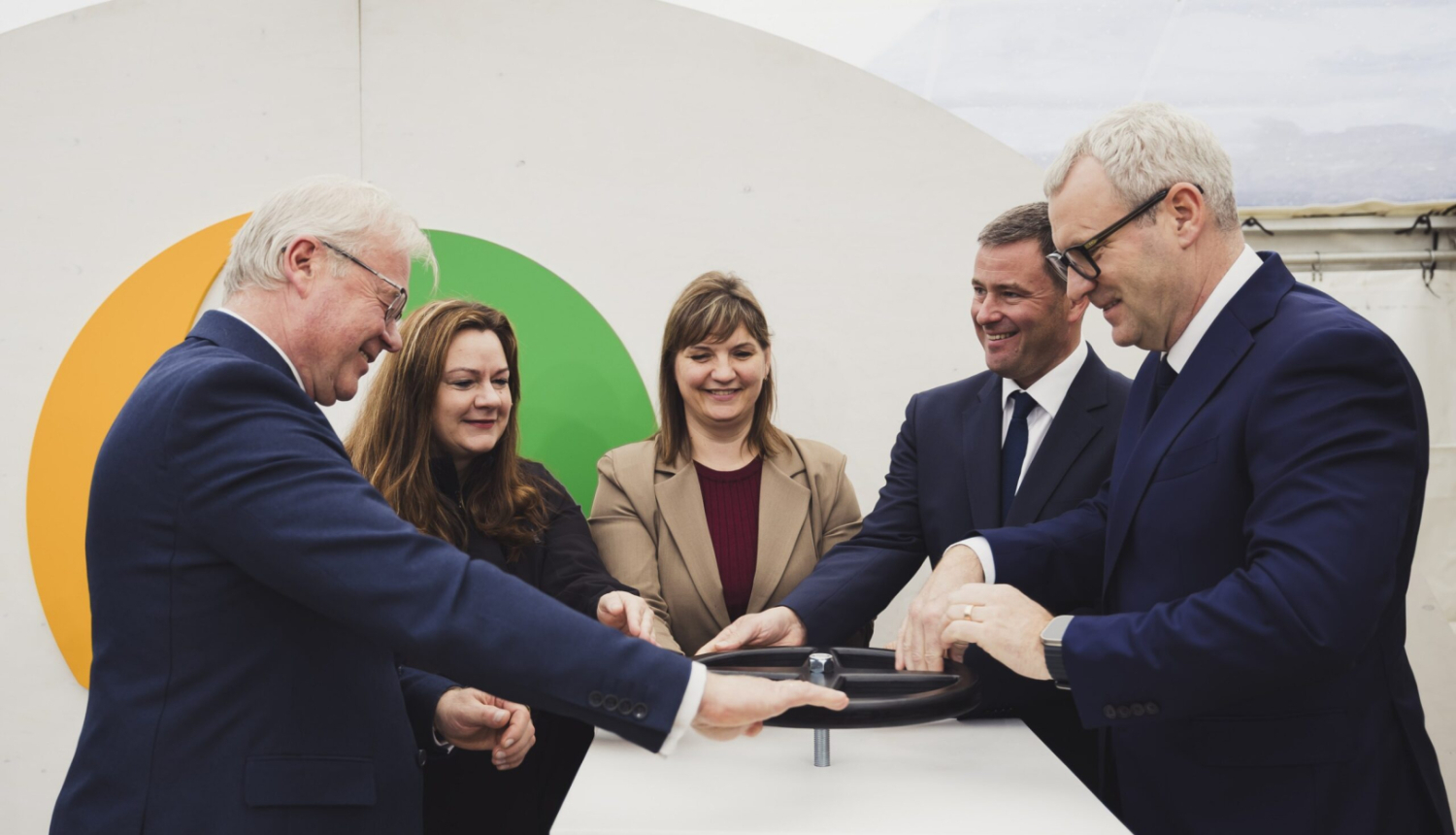 Vīrieši un sievietes uzvalkos pie simboliska vārsta