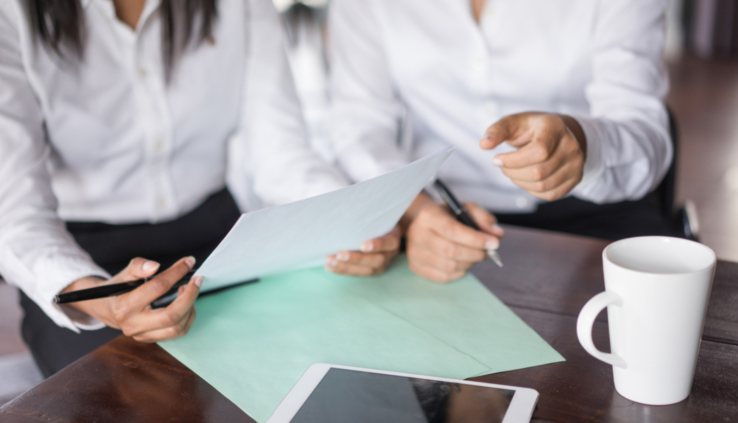 Divu kolēģu tuvplāns, kas strādā ar dokumentiem pie galda