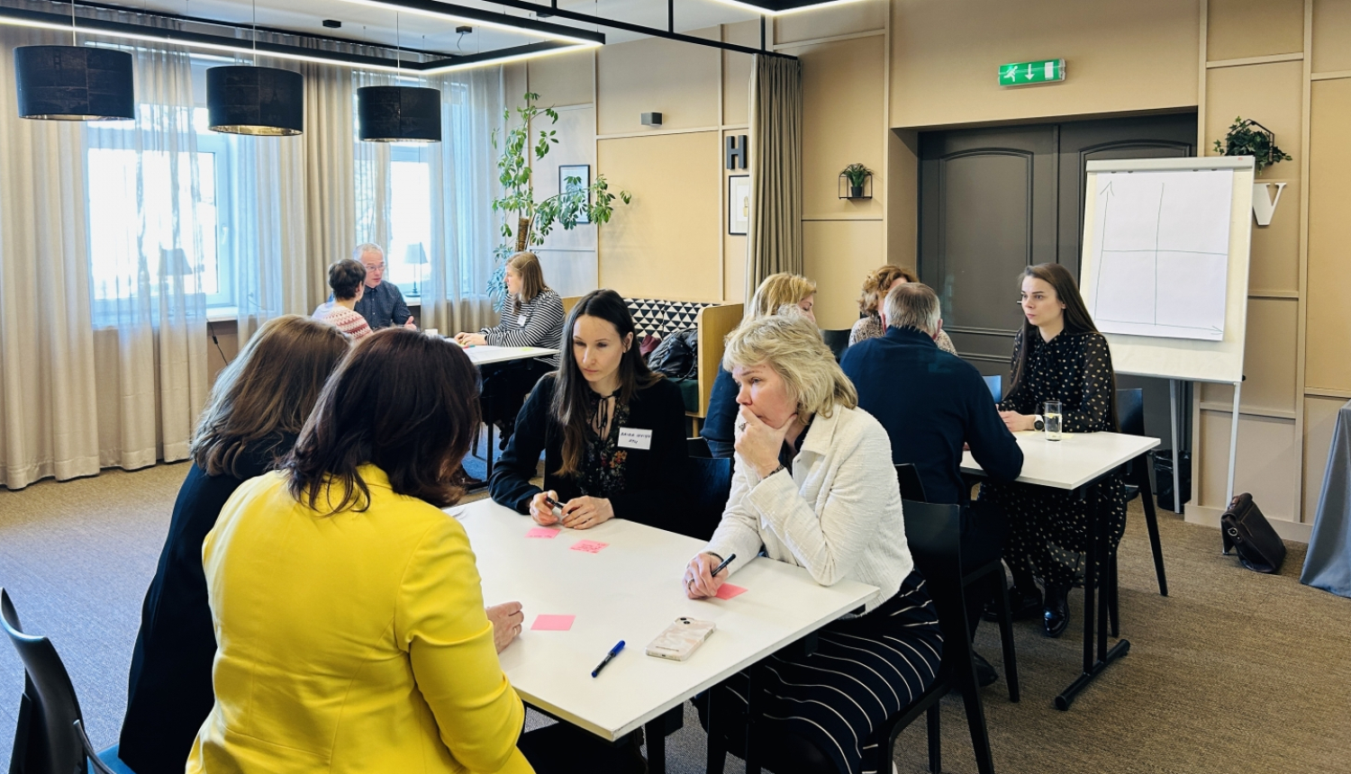 Cilvēki sēž pie apspriežu galdiem