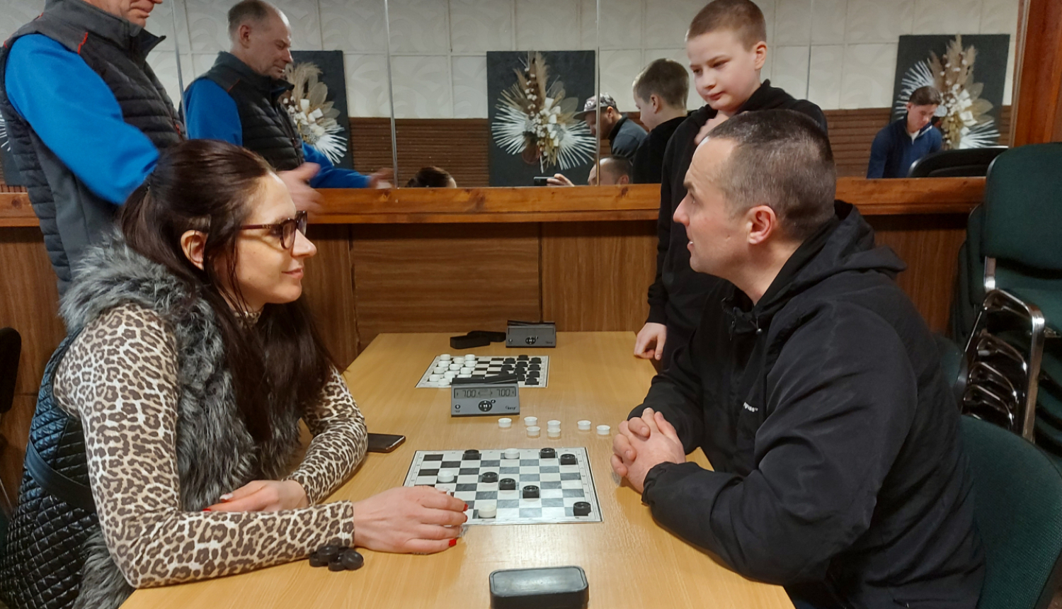 Sieviete pie galda spēlē dambreti ar vīrieti