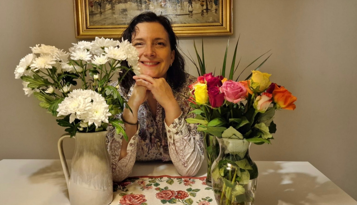 Smaidīga sieviete starp divām puķu vāzēm ar ziediem