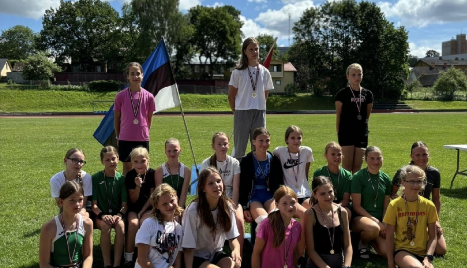 Bērni pie Latvijas un Igaunijas karogiem ārā uz zaļas zāles