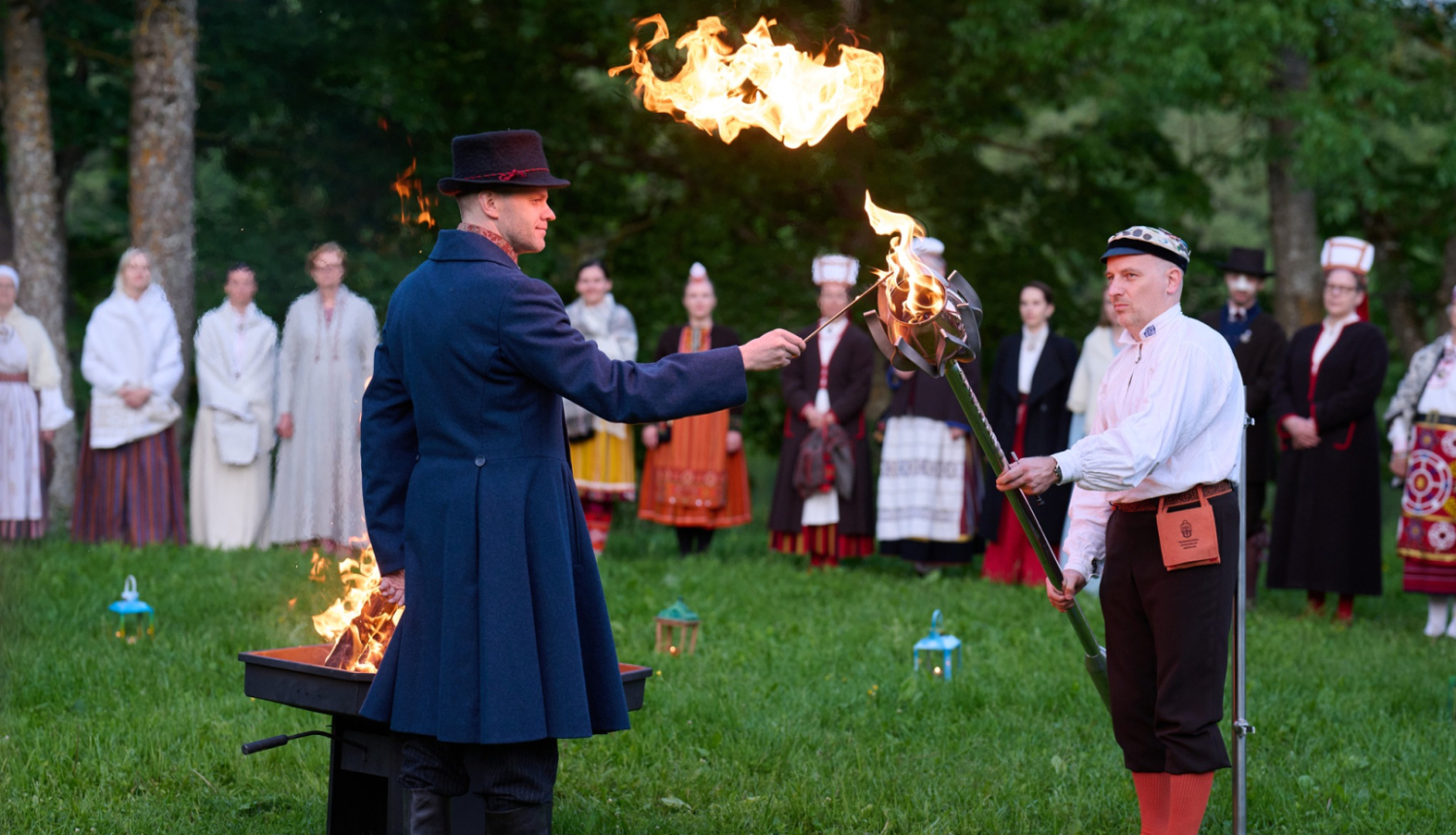 Vīrietis grenzā t;erpā aizdedzina metāla lāpu.