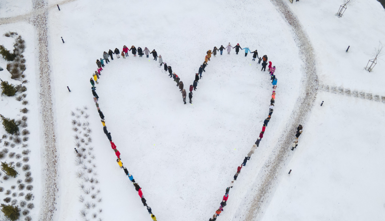 Drona foto no agšas ar cilvēkiem, kas sastājušies kopā veido sirds formu