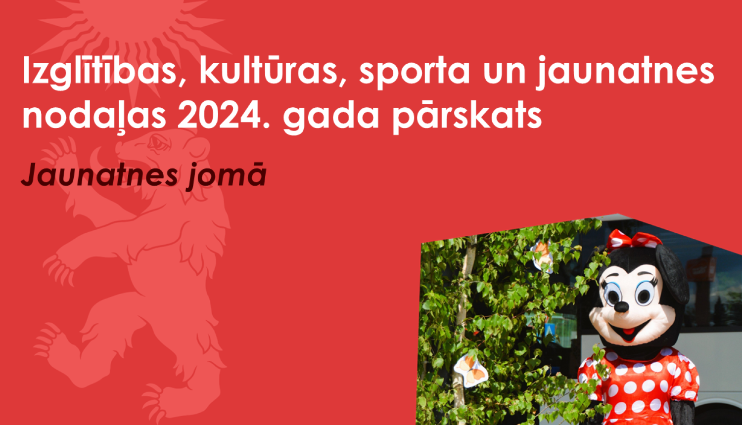 Sarkans baneris ar Valkas novada ģerboņa lāča siluetu un peles Minnijas fotogrāfiju