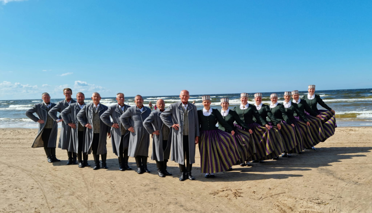 Deju kolektīvs tautas tērpos jūras piekrastē