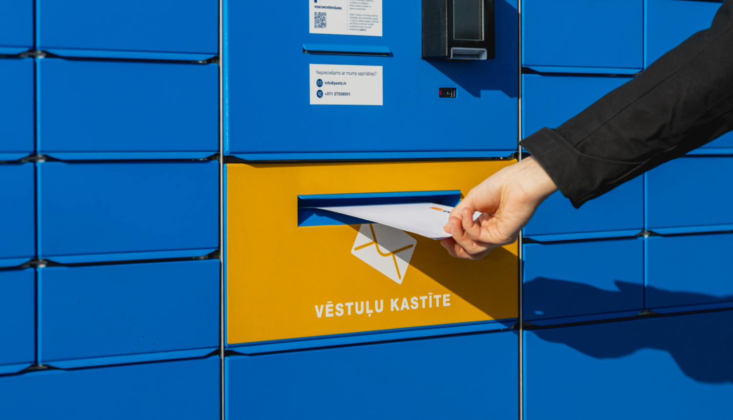 Pasta skapis zilā krāsā ar spilgti dzeltenu sadaļu ar uzrakstu "Vēstuļu kastīte".