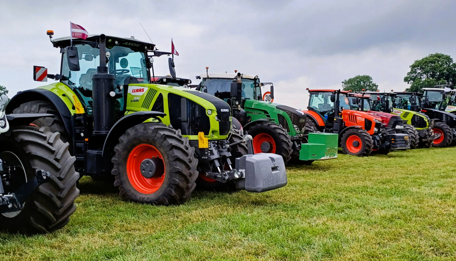 Traktori sastājušies blakus viens otram zālienā