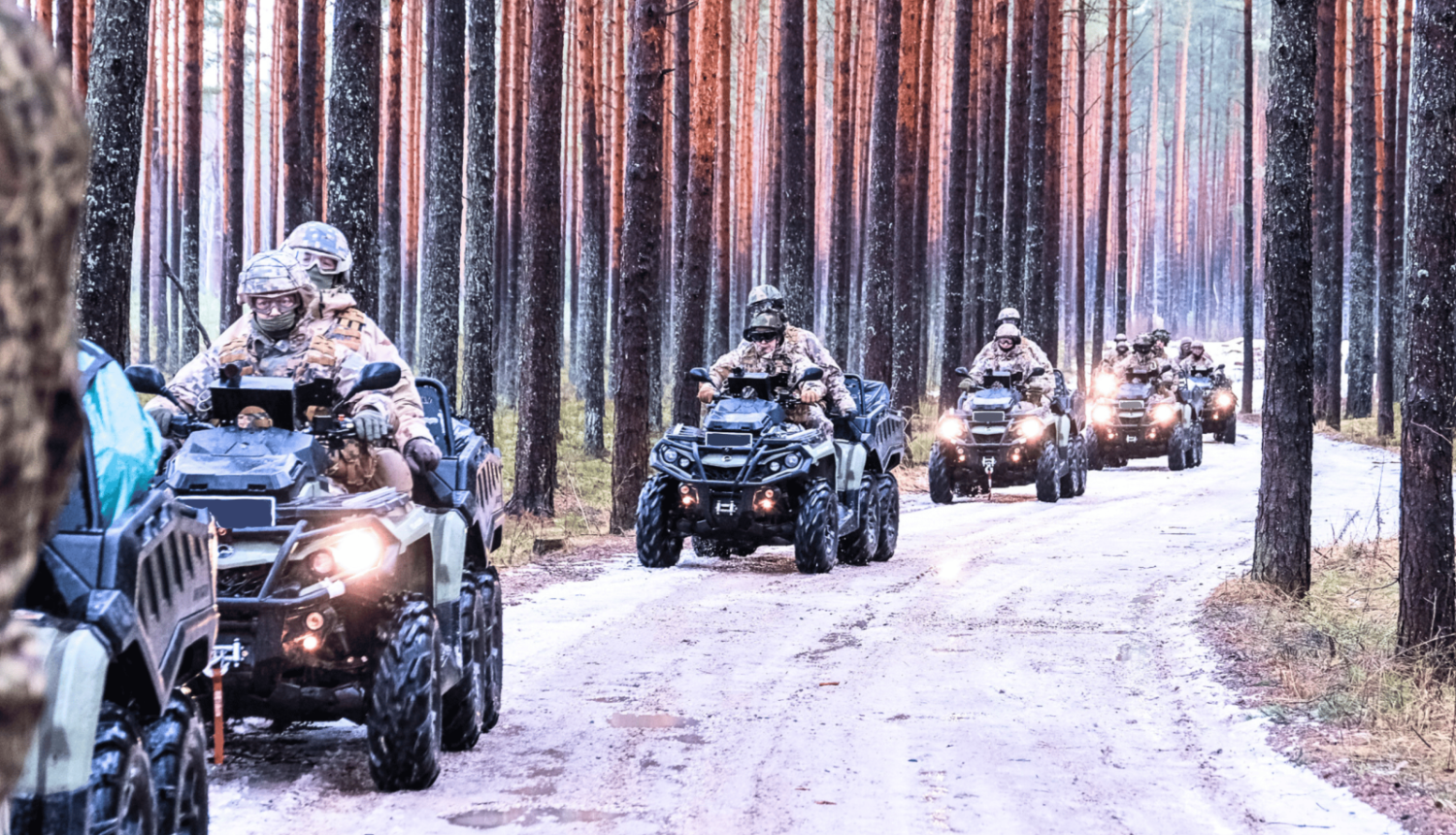 Zemessargi formas tērpos uz kvadracikliem uz ceļa mežā