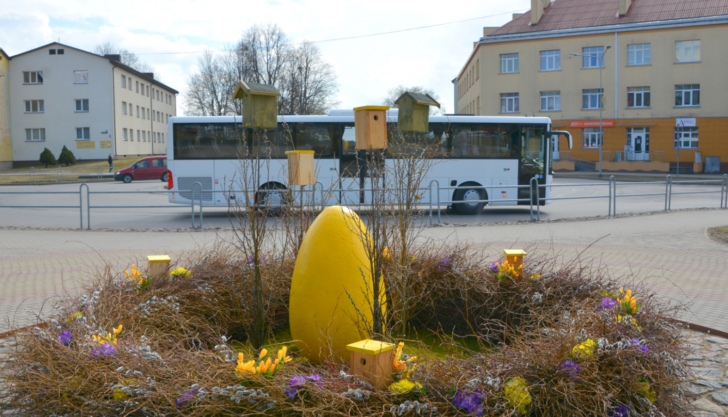 Lieldienu dekorācija - ola grozā priekšplānā un autobuss fonā