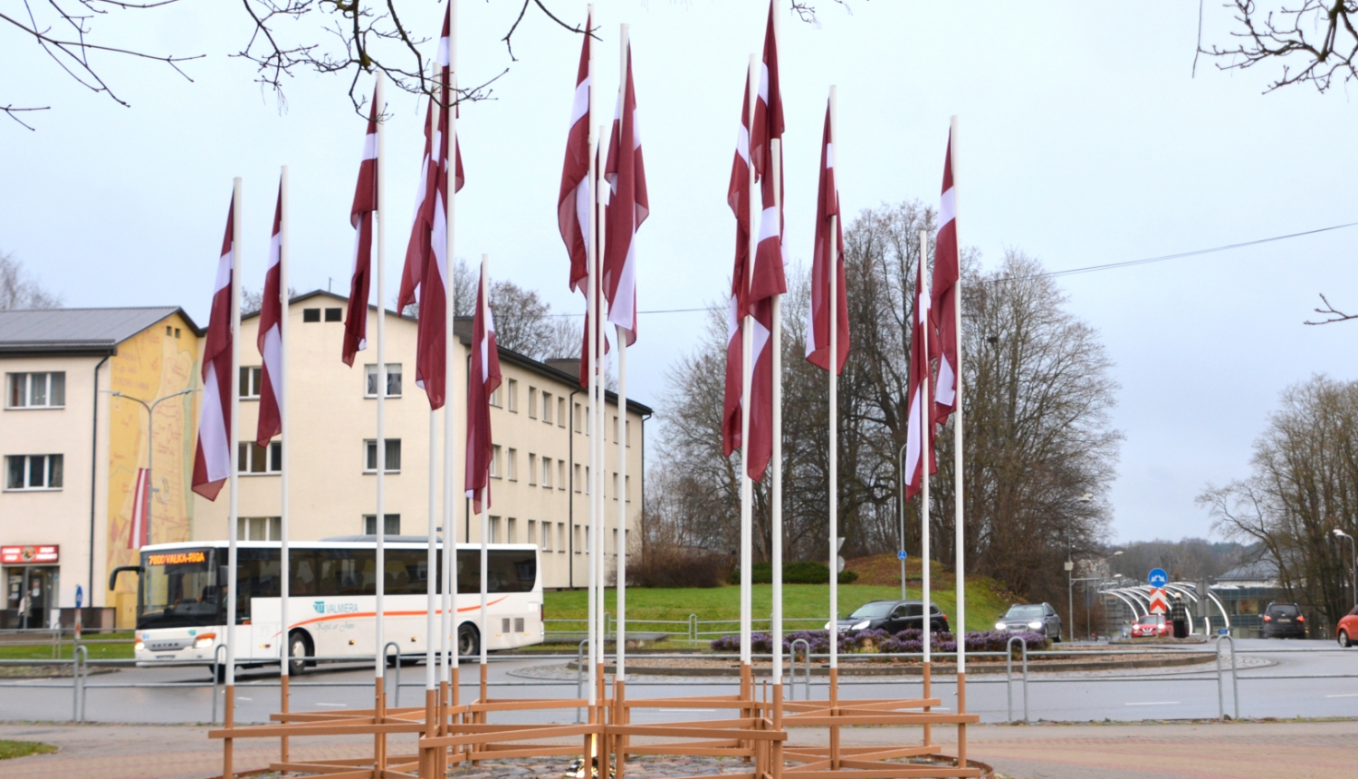 Latvijas karogu ornaments pie Valmieras apļa pilsētas centrā ar baltu autobusu fonā