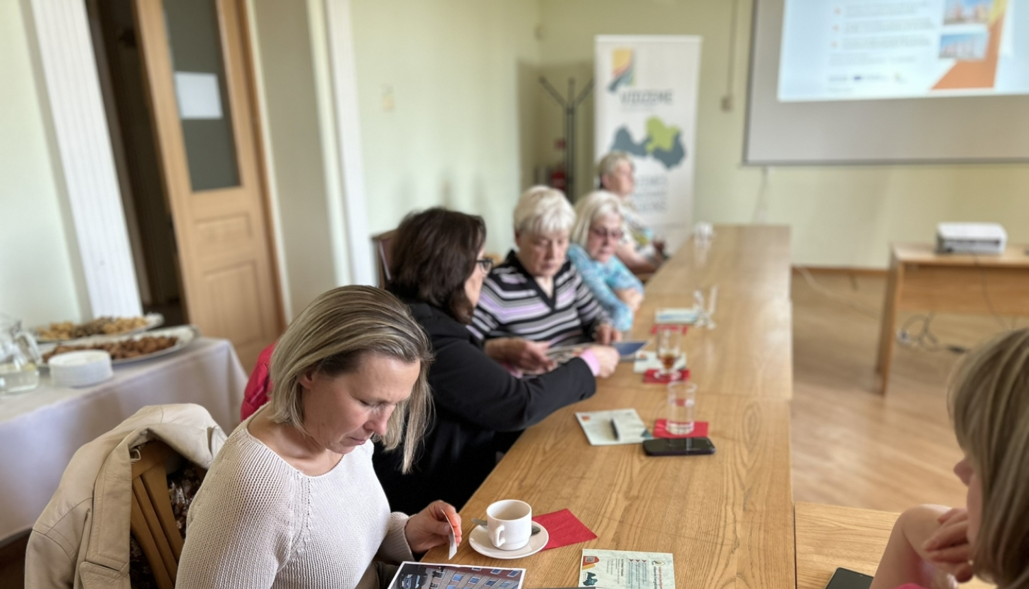 Sieviete pie galda skatās prezentācijas materiālos