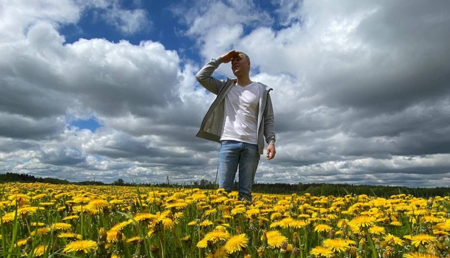 Vīrietis pieneņu laukā lūkojas tālumā