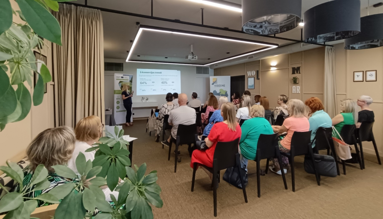 Semināra zāle ar sēdošiem cilvēkiem