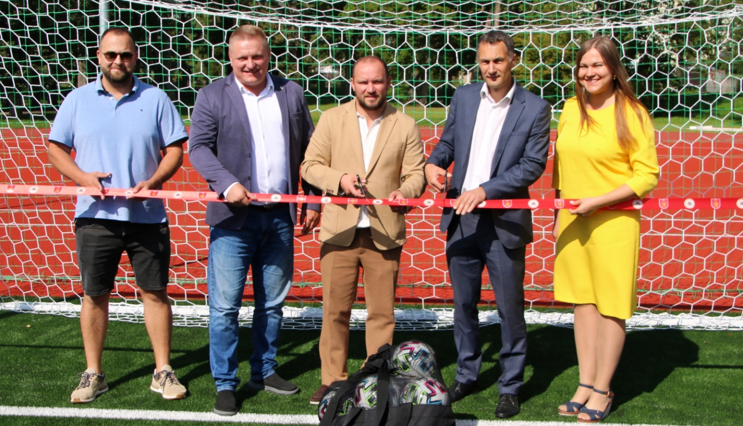 Amatpersonas pie futbola vārtierm, svinīgās lentes griešana