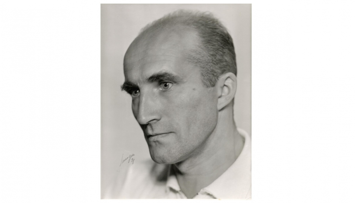 Jāņa Indusa portrets, vīrietis pušmūža gados ar īsiem matiem.