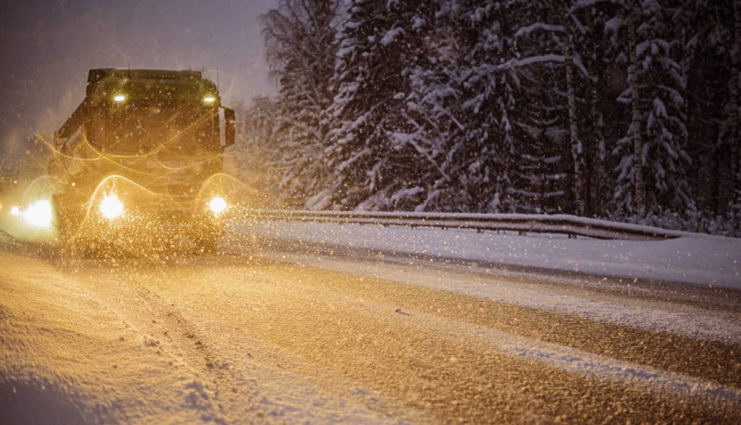 Smagais kravas auto uz sniegota ceļa tumšajā diennakts laikā