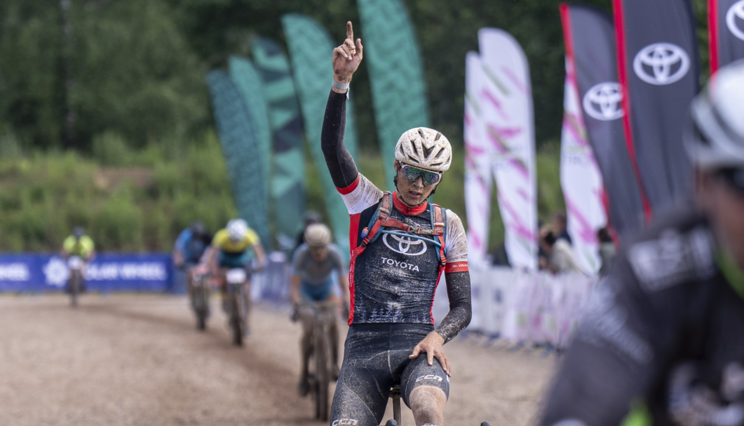 Velosipēdists dubļos ar paceltu roku 