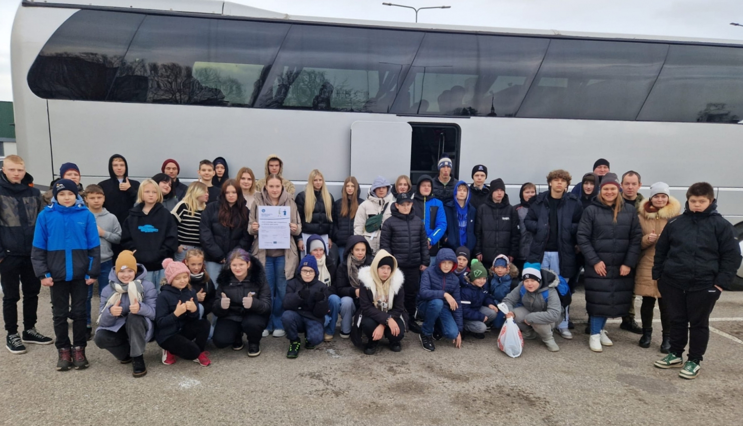 Audzēkņu un treneru kopbilde pie autobusa