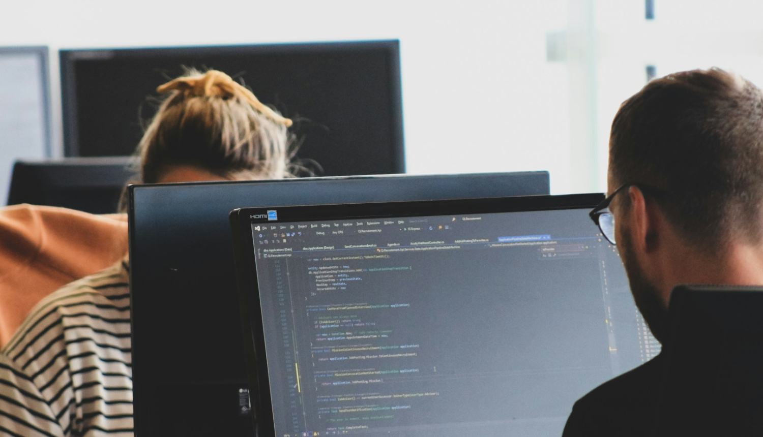 Vīrietis un sieviete sēž pie datoru monitoriem