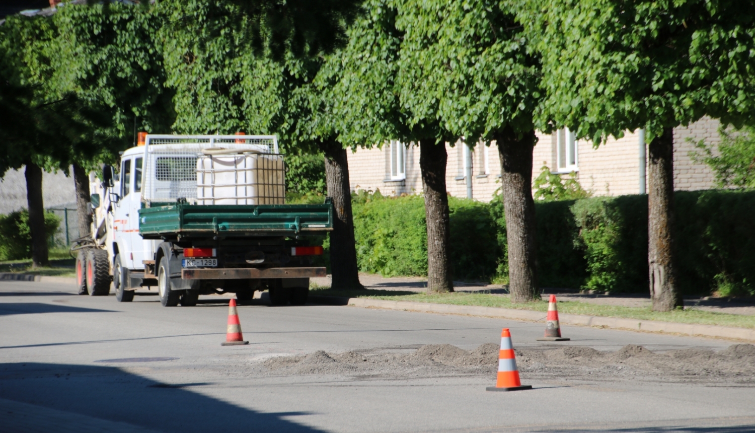 Ielas ceļš ar oranžajiem konusiņiem un remonstrādnieku busiņu
