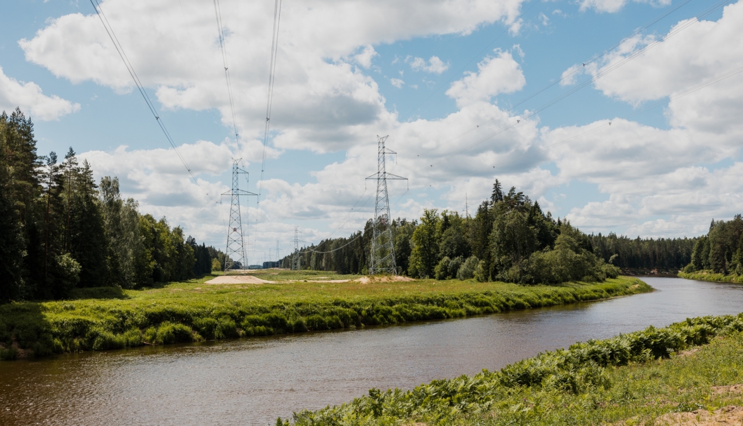 Upe ar augstsprieguma vadu torņiem fonā