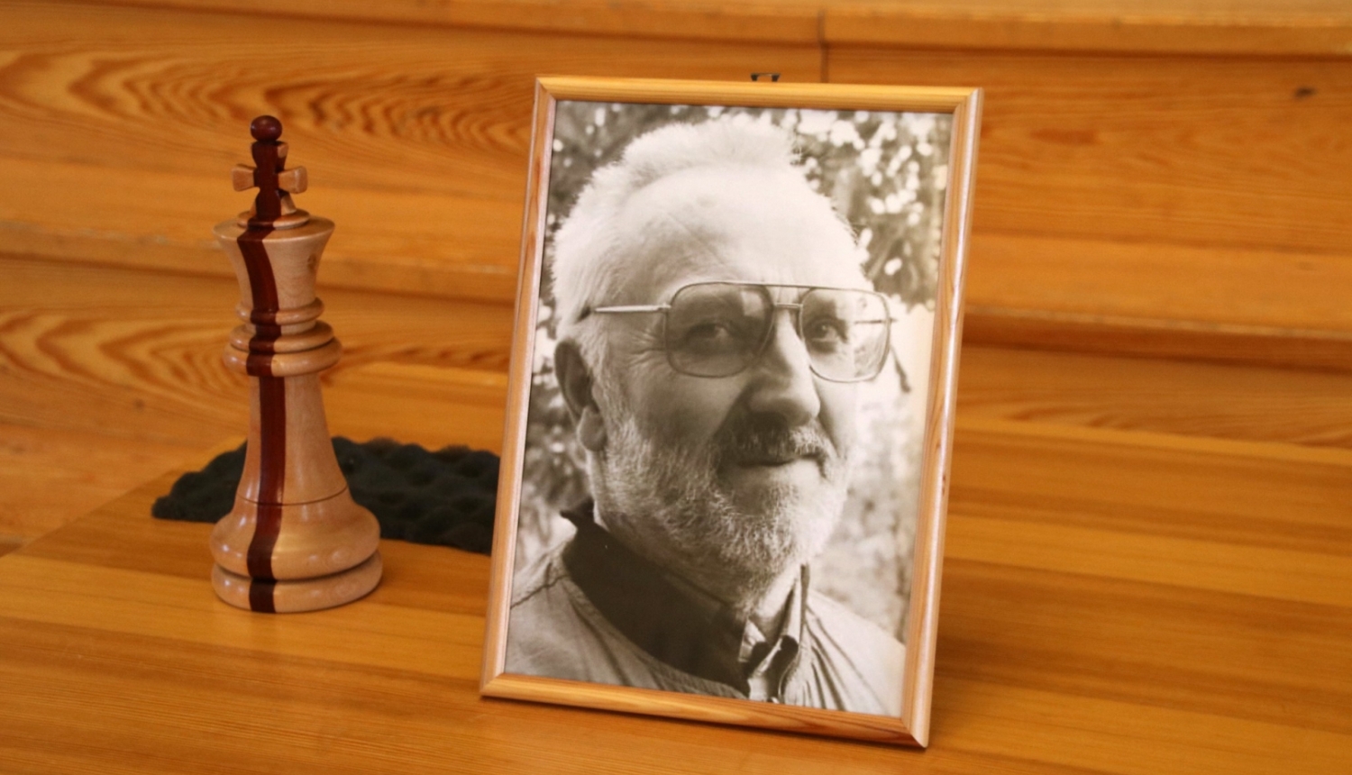 Vsevoloda Dudzinksa portretfotogrāfija blakus no koka izgrebtai šaha figūrai